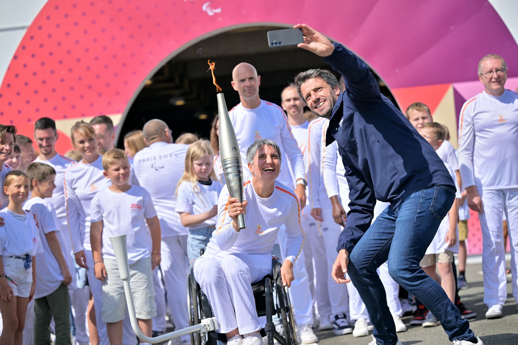 French President of the Paris 2024 Olympics and Paralympics Organising Committee (COJO) Tony Estanguet (R) takes a selfie with Former French wheelchair fencer Emmanuelle Assmann holding the torch of the Paris 2024 Paralympic Games after arrival of the Paralympics flame at the entrance of the Channel Tunnel in Coquelles, northern France on August 25, 2024. The Paris 2024 Paralympics flame was lit in Stoke Mandeville of England and it will pass through the Channel Tunnel with 24 British torchbearers taking it halfway to hand over to 24 French torchbearers, who will take the torches to Calais, then 12 torches will travel across France from August 25, 2024 to August 28.,Image: 901427093, License: Rights-managed, Restrictions: , Model Release: no, Credit line: LOU BENOIST / AFP / Profimedia