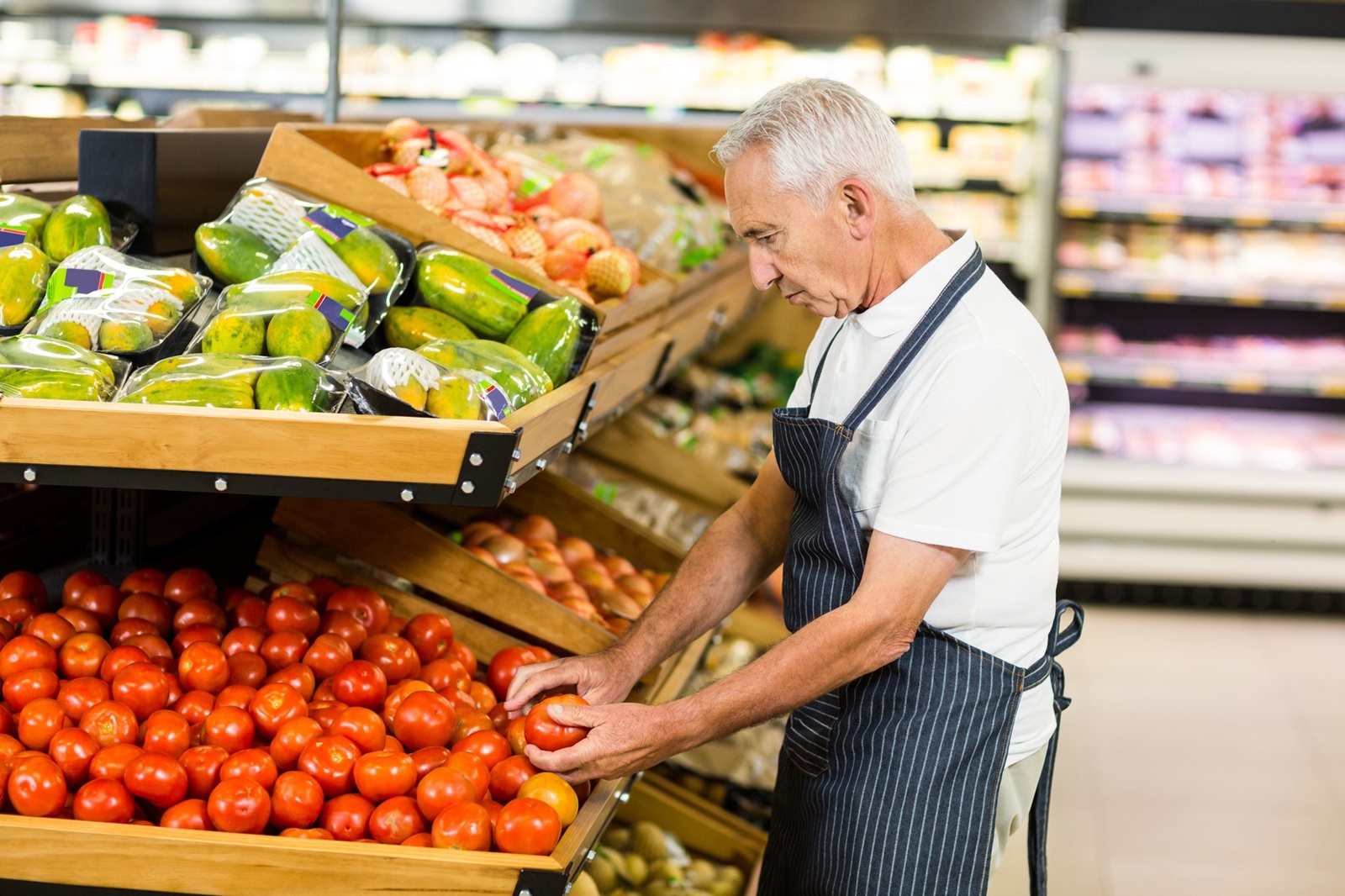 Serious senior worker taking tomato in supermarket,Image: 279960134, License: Royalty-free, Restrictions: , Model Release: yes, Credit line: - / Wavebreak / Profimedia