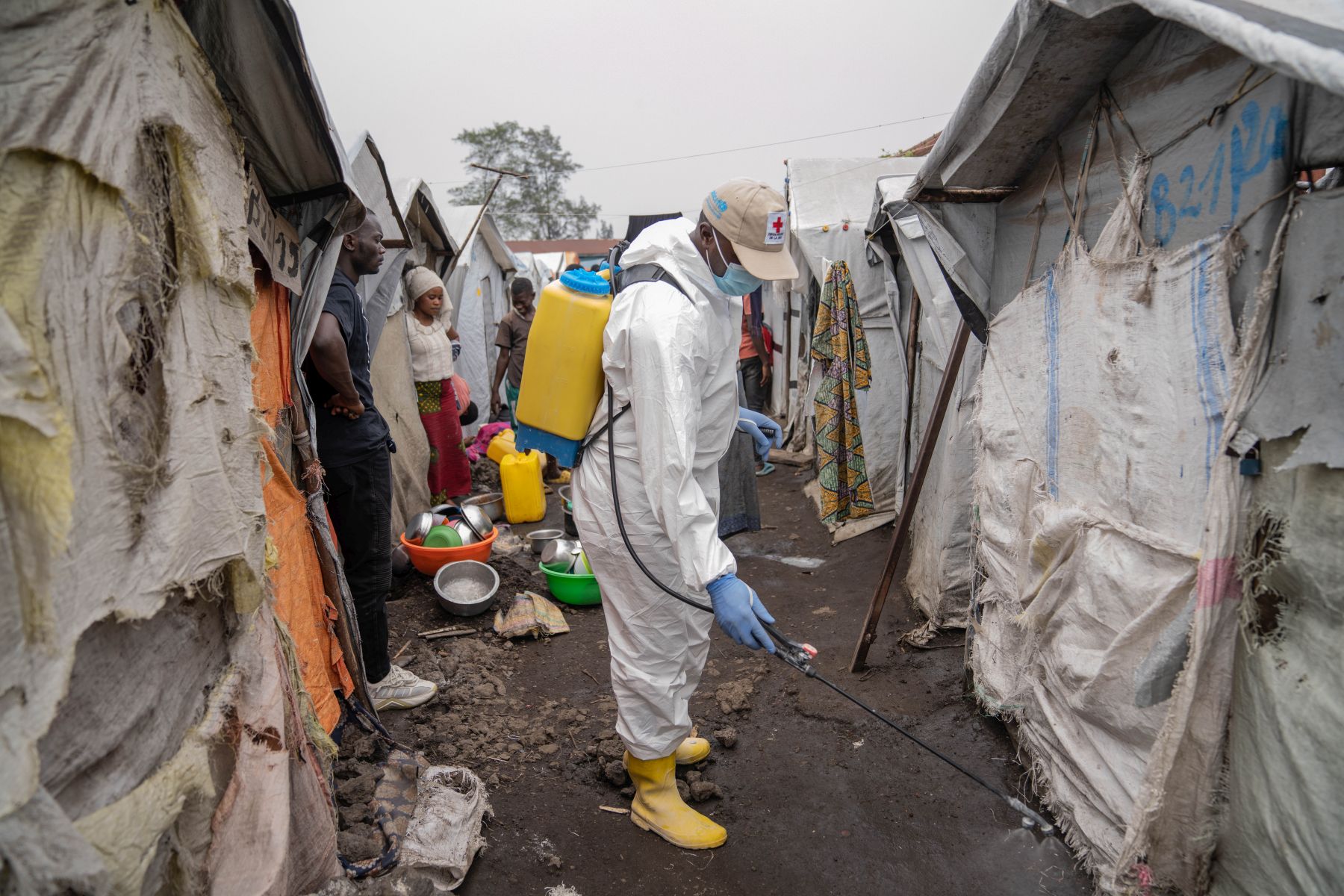 epa11559884 A Red Cross worker sprays chlorine as other Red Cross personnel raised awareness about mpox and hygiene among internally displaced people in the Don Bosco camps in Goma, Democratic Republic of Congo, 22 August 2024. The World Health Organization has declared the ongoing outbreaks of monkeypox (MPOX) in Congo and elsewhere in Africa a global emergency. Mpox causes fever, rash, and lesions all over the body, severe headaches, and fatigue.  EPA/MOISE KASEREKA