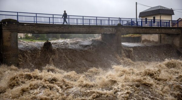 epa11603534 A local man walks on a bridge over the overflowing Bela river in Mikulovice, Czech Republic, 14 September 2024. The Czech Hydrometeorological Institute (CHMU) has issued a extreme precipitation warning of unusually intense rainfall which can significantly raise water levels and that will affect the Czech Republic from 12 September until the end of the week.  EPA/MARTIN DIVISEK