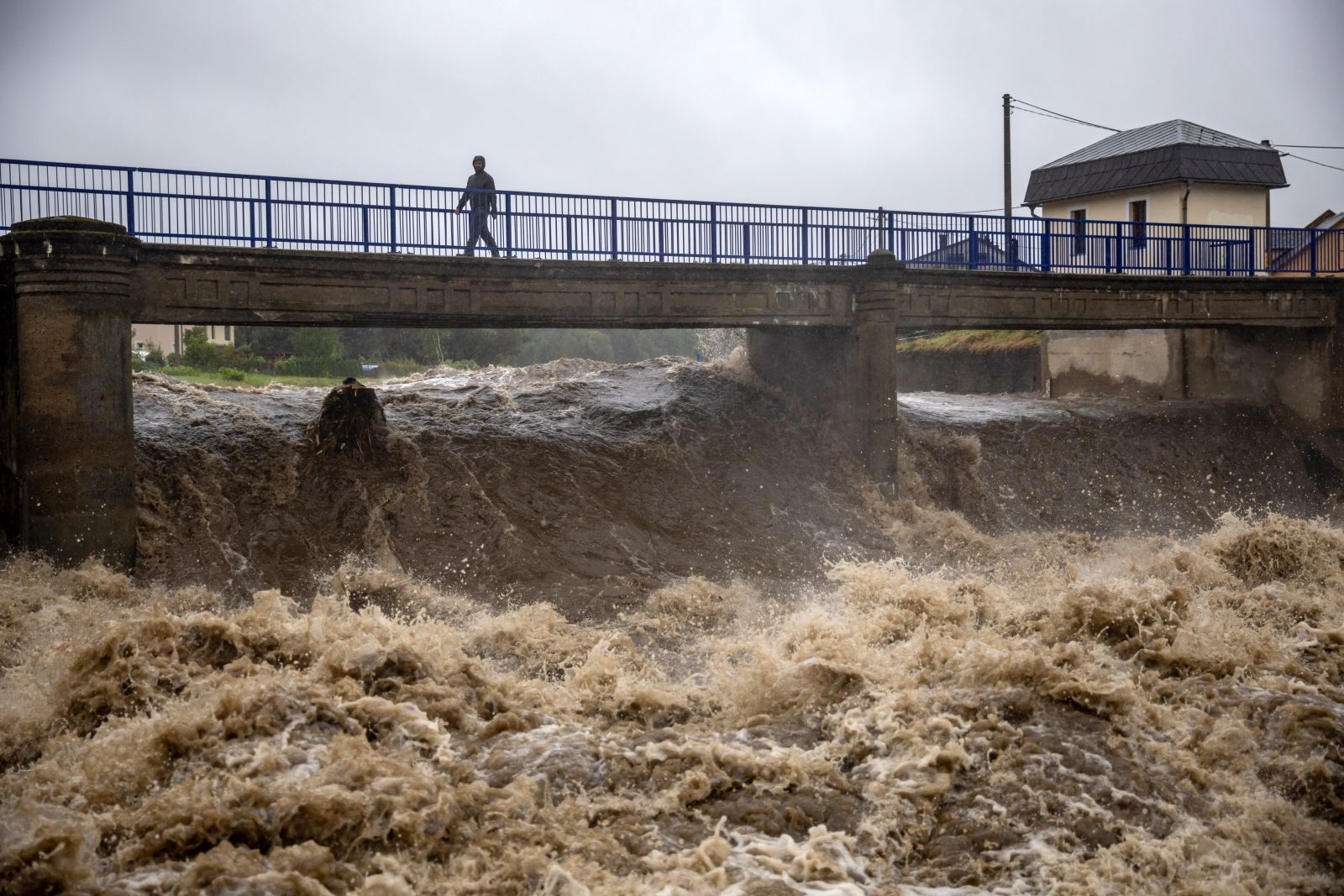 epa11603534 A local man walks on a bridge over the overflowing Bela river in Mikulovice, Czech Republic, 14 September 2024. The Czech Hydrometeorological Institute (CHMU) has issued a extreme precipitation warning of unusually intense rainfall which can significantly raise water levels and that will affect the Czech Republic from 12 September until the end of the week.  EPA/MARTIN DIVISEK