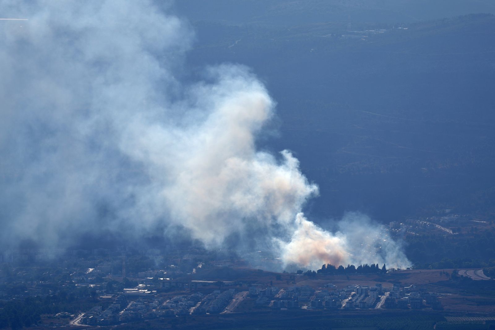 epa11611961 Smoke rises as a result of projectiles fired from southern Lebanon over Kiryat Shmona, northern Israel, 18 September 2024. The Israeli military stated that several missiles fired from Lebanon crossed into Israeli territory and were intercepted by the Iron Dome air defense system.  EPA/ATEF SAFADI