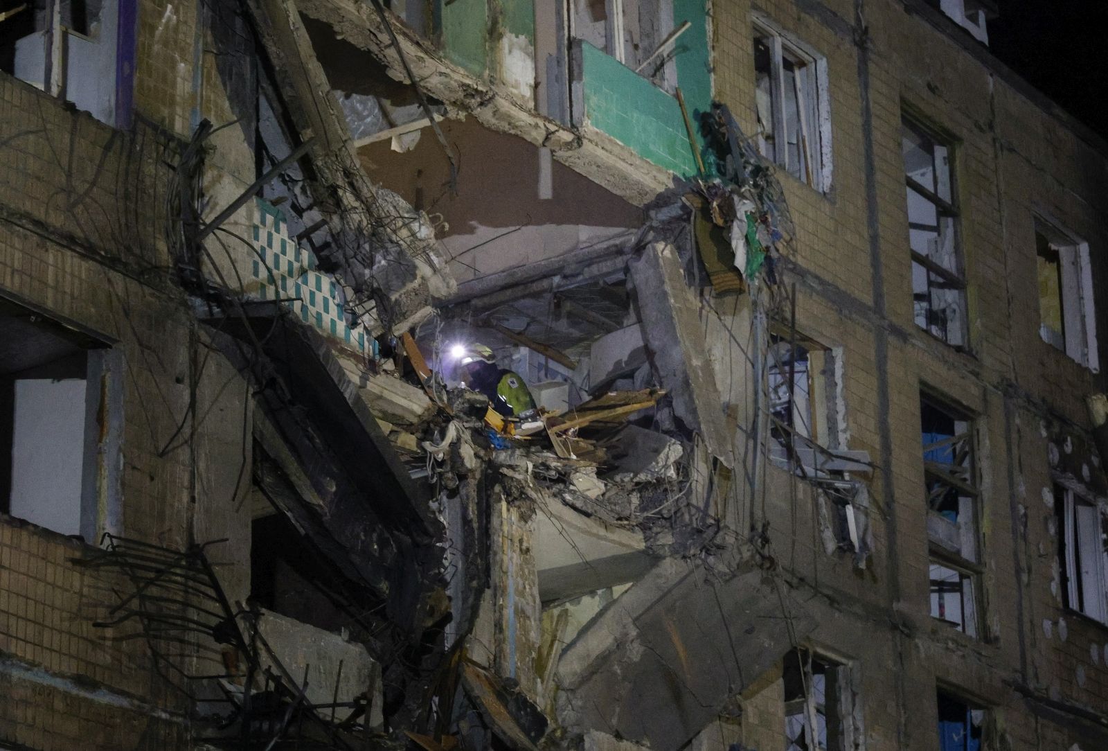 epa11639191 Ukrainian rescuers work at the site of a shelling on a residential building in Kharkiv, northeastern Ukraine, late 02 October 2024 (issued 03 October 2024), amid the ongoing Russian invasion. At least 10 people were injured, including a three-year-old girl, following a Russian glide bomb shelling in a residential area of Kharkiv, according to the State Emergency Service of Ukraine.  EPA/SERGEY KOZLOV