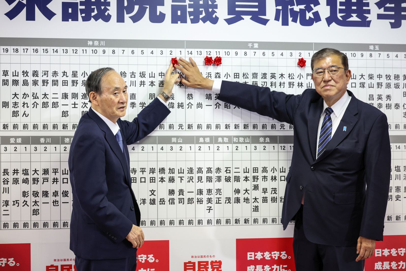 epa11687005 Japan's Prime Minister Shigeru Ishiba (R) and Yoshihide Suga, Vice President of Japan's Liberal Democratic Party (LDP), place a pin on a board showing candidate's names while speaking to the media at the LDP's headquarters, Tokyo, Japan, 27 October 2024. Exit polling suggested that the incumbent LDP would not be able to form a single-party majority government in a snap election called by Prime Minister Shigeru Ishiba.  EPA/TAKASHI AOYAMA / POOL