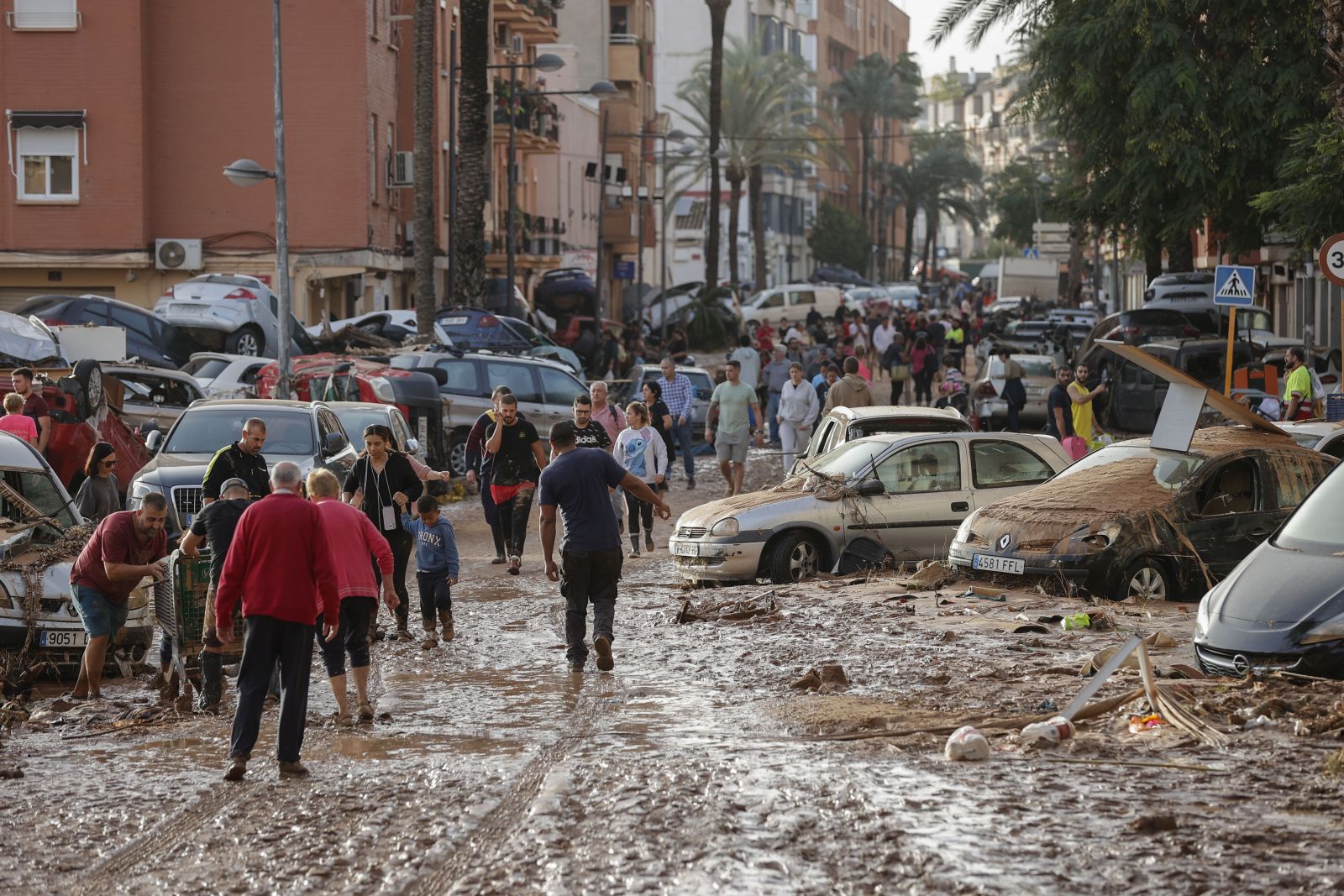 epa11692839 Residents walk along a mud-covered street in the flood-hit municipality of Paiporta, in the province of Valencia, Spain, 30 October 2024. The intense rainfall impacting the eastern part of the country resulted in at least 70 lives being lost in the province of Valencia and neighboring provinces due to the flooding. The mayor of Paiporta, located about ten kilometers southwest of Valencia, confirmed that at least 34 people died in the municipality due to the flooding. The State Meteorological Agency (AEMET) issued orange and red alerts for rainfall in multiple regions of east and southern Spain due to a DANA (isolated depression at high levels) phenomenon.  EPA/MANUEL BRUQUE