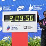 Oct 13, 2024; Chicago, IL, USA; Ruth Chepngetich of Kenya poses for a photo with the time clock after finishing first in the womens race, setting a new world record at 2:09:56 during the Chicago Marathon at Grant Park. Mandatory Credit: Patrick Gorski-Imagn Images Photo: Patrick Gorski/REUTERS