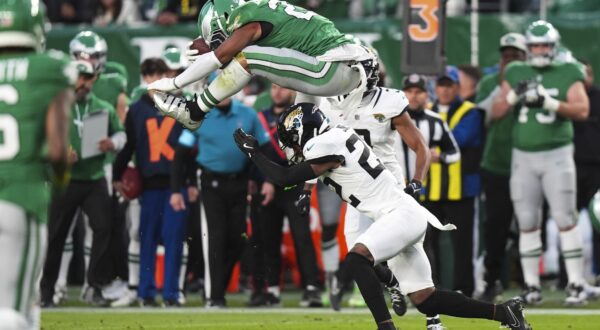 Philadelphia Eagles running back Saquon Barkley (26) hurdles over Jacksonville Jaguars cornerback Jarrian Jones (22) during the first half of an NFL football game Sunday, Nov. 3, 2024, in Philadelphia. (AP Photo/Chris Szagola)