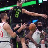 LA Clippers guard James Harden, right, passes the ball behind the back of Boston Celtics center Kristaps Porzingis (8) to Ivica Zubac (40) during the first half of an NBA basketball game, Monday, Nov. 25, 2024, in Boston. (AP Photo/Charles Krupa) Clippers Celtics Basketball