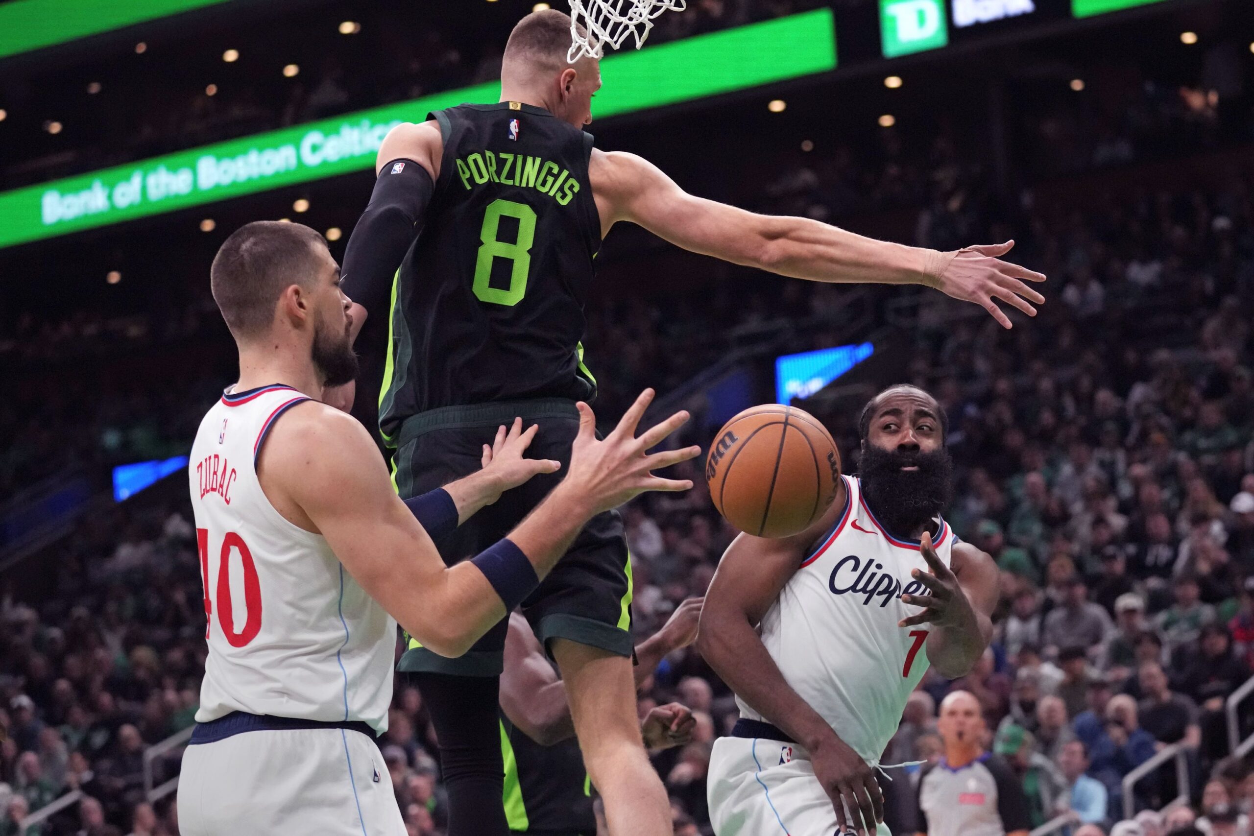 LA Clippers guard James Harden, right, passes the ball behind the back of Boston Celtics center Kristaps Porzingis (8) to Ivica Zubac (40) during the first half of an NBA basketball game, Monday, Nov. 25, 2024, in Boston. (AP Photo/Charles Krupa) Clippers Celtics Basketball