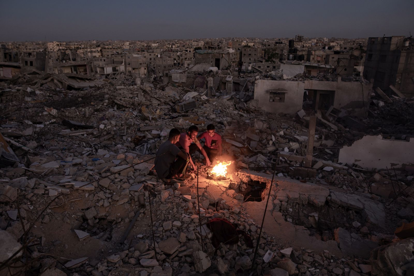 epa11671648 Palestinians sit next to a fire on the rubble of their destroyed home in Khan Yunis, southern Gaza Strip, 20 October 2024. More than 42,500 Palestinians and over 1,400 Israelis have been killed, according to the Palestinian Health Ministry and the Israel Defense Forces (IDF), since Hamas militants launched an attack against Israel from the Gaza Strip on 07 October 2023, and the Israeli operations in Gaza and the West Bank that followed it.  EPA/HAITHAM IMAD