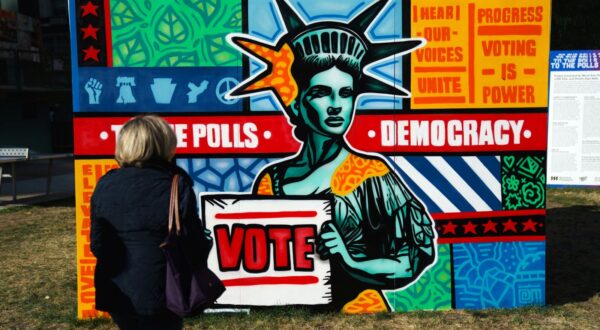 epa11690600 A woman passes signs encouraging early voting near Philadelphia City Hall in Philadelphia, Pennsylvania, USA, 29 October 2024.  EPA/WILL OLIVER