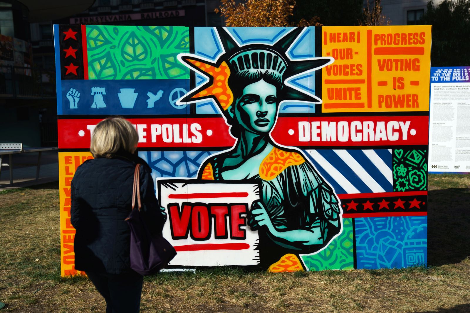 epa11690600 A woman passes signs encouraging early voting near Philadelphia City Hall in Philadelphia, Pennsylvania, USA, 29 October 2024.  EPA/WILL OLIVER