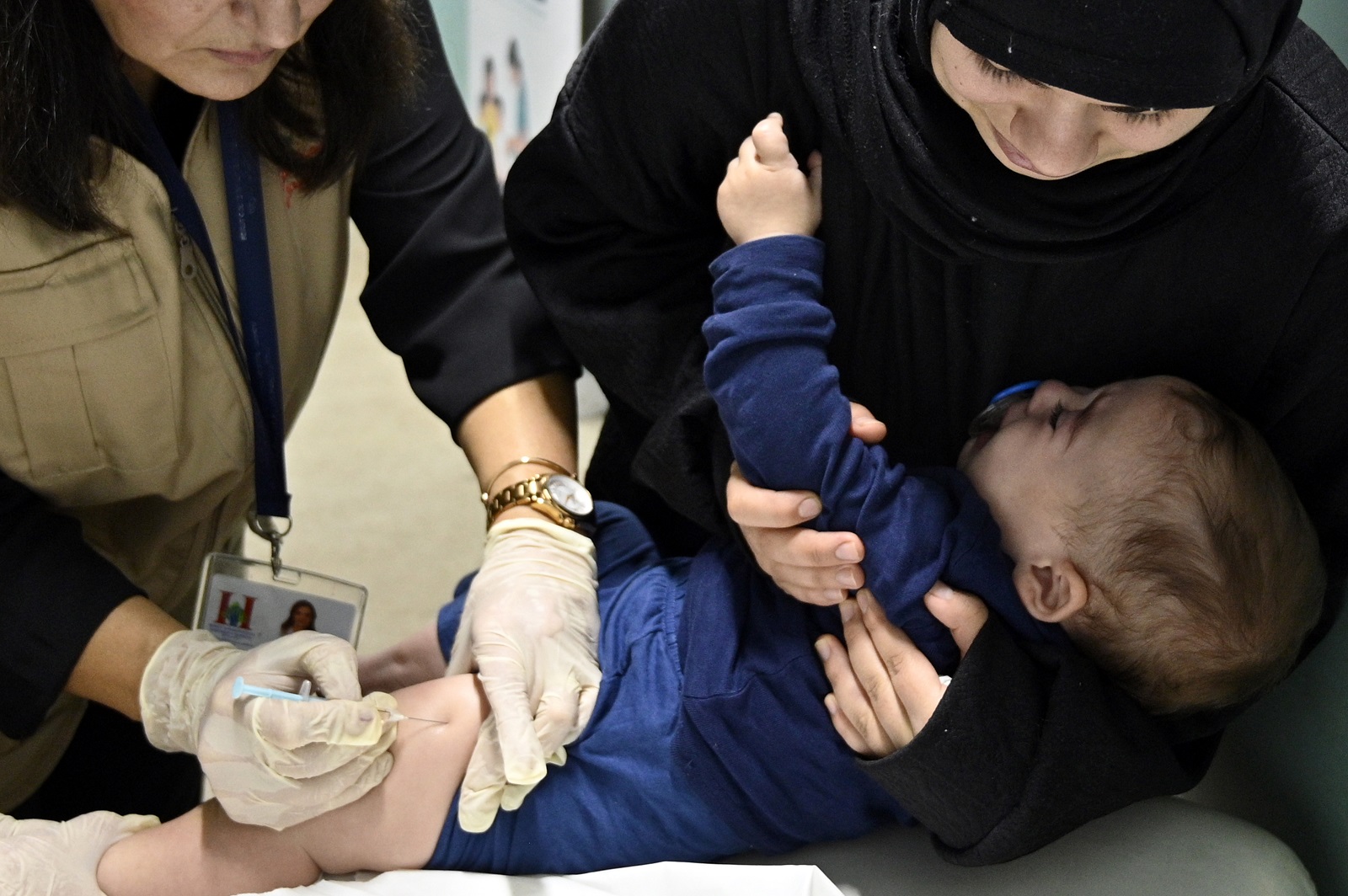 epa11720501 A parent comforts her daughter while a healthcare worker administers a measles vaccine to a child at a shelter for the displaced in the Karantina area in Beirut, Lebanon, 14 November 2024. Health workers give polio and measles vaccines to displaced children at one of the centers that houses more than 700 people who fled Israeli attacks from southern Lebanon, Beirut southern suburb and the Bekaa Valley. According to the Lebanese Ministry of Health, around 3,365 people have been killed and over 14,344 others have been injured in Lebanon since the escalation in hostilities between Israel and Hezbollah. EPA/WAEL HAMZEH  EPA-EFE/WAEL HAMZEH