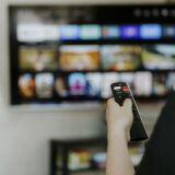 Hand holding remote control pointing to TV. Person watching smart television indoors. Blurred background. Colorful screen, copy space. Woman finger in foreground pressing button. Movie stream service,Image: 901731439, License: Royalty-free, Restrictions: , Model Release: no, Credit line: Lena Ivanova / imageBROKER / Profimedia