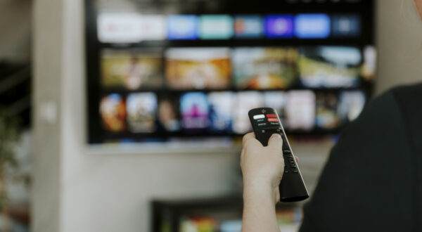 Hand holding remote control pointing to TV. Person watching smart television indoors. Blurred background. Colorful screen, copy space. Woman finger in foreground pressing button. Movie stream service,Image: 901731439, License: Royalty-free, Restrictions: , Model Release: no, Credit line: Lena Ivanova / imageBROKER / Profimedia