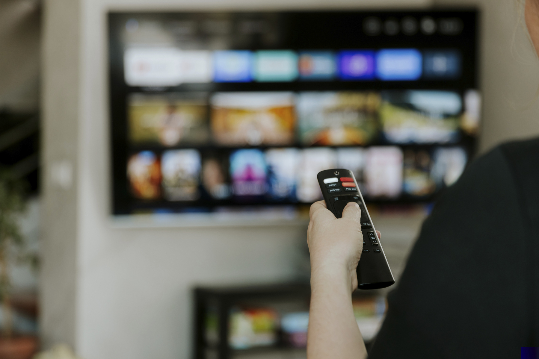 Hand holding remote control pointing to TV. Person watching smart television indoors. Blurred background. Colorful screen, copy space. Woman finger in foreground pressing button. Movie stream service,Image: 901731439, License: Royalty-free, Restrictions: , Model Release: no, Credit line: Lena Ivanova / imageBROKER / Profimedia