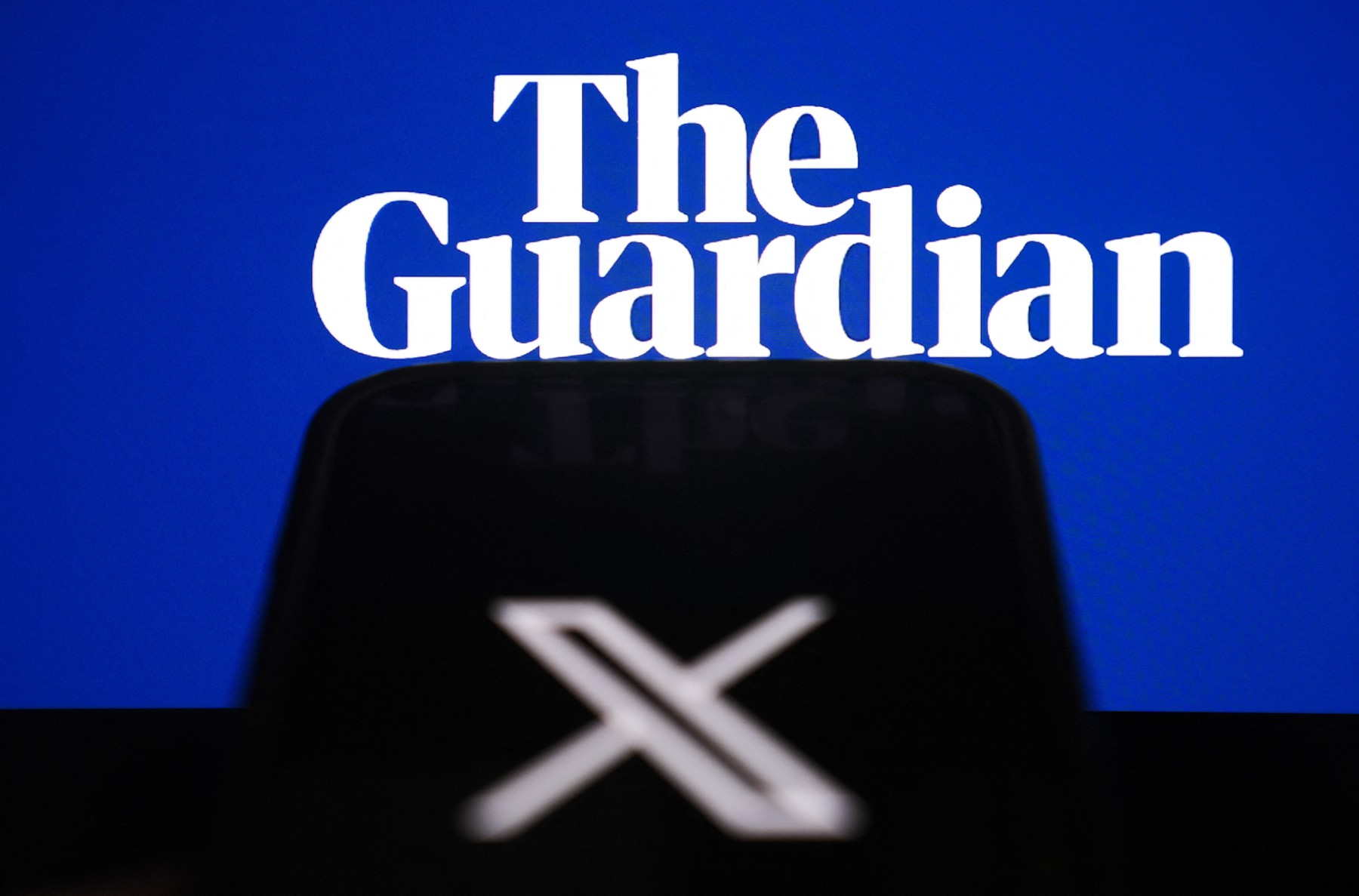 ANKARA, TURKIYE - NOVEMBER 13: The logo of 'X' is seen on a mobile screen in front 'The Guardian' logo in Ankara, Turkiye on November 13, 2024. Muhammed Selim Korkutata / Anadolu,Image: 933916997, License: Rights-managed, Restrictions: , Model Release: no, Credit line: Muhammed Selim Korkutata / AFP / Profimedia