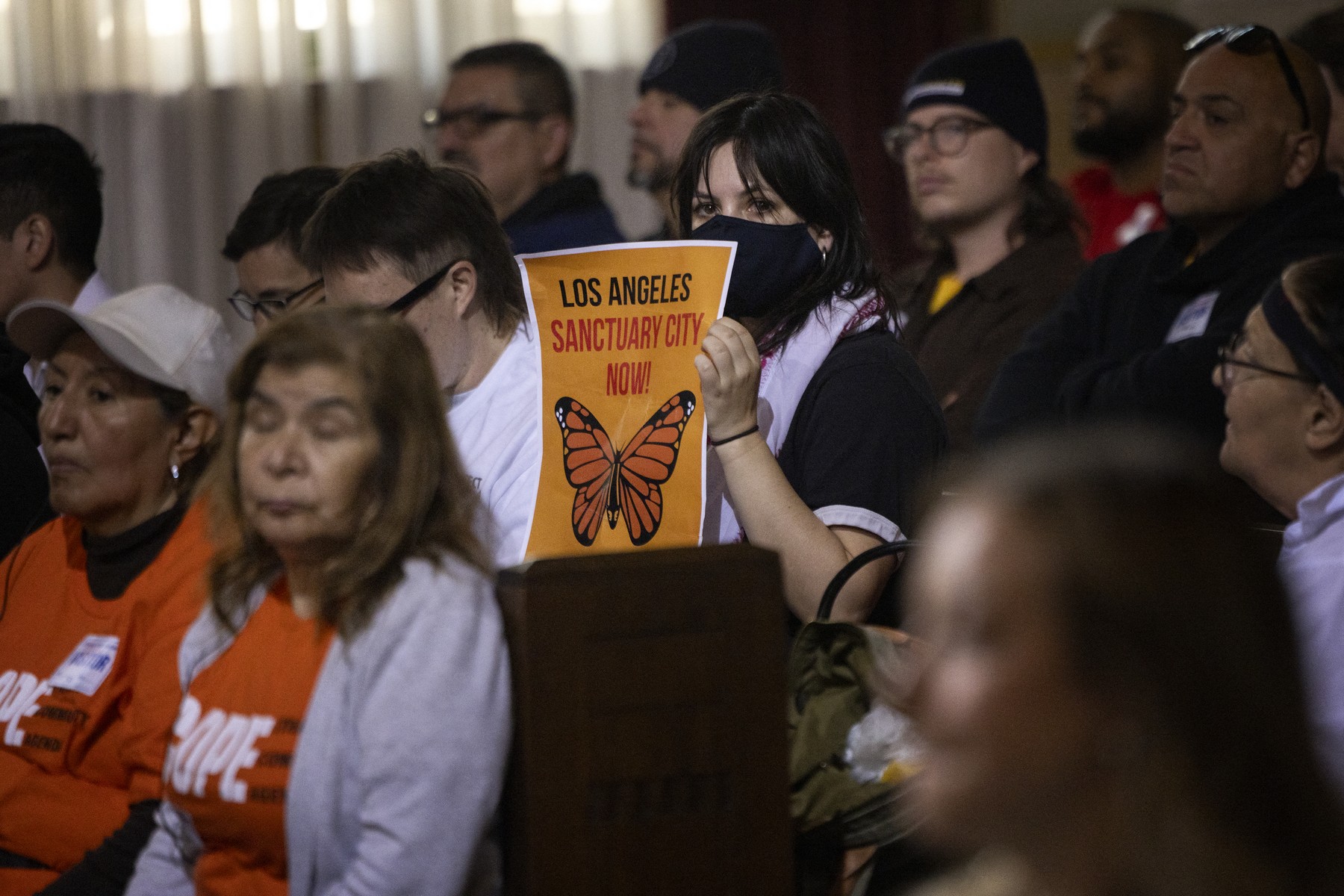 A woman in the audience holds up a poster with a message of support for immigrants as the Los Angeles City Council considers a "sanctuary city" ordinance during a meeting at City Hall in Los Angeles, California, on November 19, 2024.  The proposed sanctuary city ordinance would prohibit any city resources from being used  to help federal enforcement of immigration laws.,Image: 936525210, License: Rights-managed, Restrictions: , Model Release: no, Credit line: ETIENNE LAURENT / AFP / Profimedia