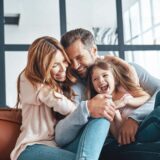 Happy young family smiling and embracing while bonding together at home