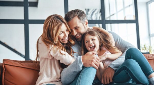 Happy young family smiling and embracing while bonding together at home