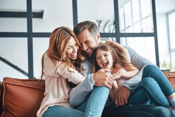 Happy young family smiling and embracing while bonding together at home