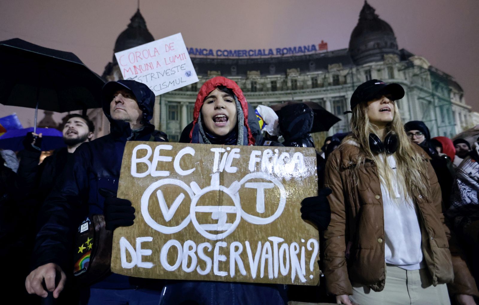 epa11748603 Romanian protesters shout slogans and hold up placards while braving the rain during a protest at the University Plaza, against far-right independent presidential candidate Calin Georgescu, in central Bucharest, Romania, 29 November 2024. Students and civil rights activists continue their protests against the far-right independent runoff candidate Calin Georgescu, whose declarations worried human right activists. Romania's Constitutional Court (CCR) on 28 November instructed the Central Electoral Bureau (BEC) to recount all ballots from the first round of presidential elections held on 24 November, following complaints from two candidates. On 29 November the court announced that the final decision had been postponed until 02 December, the day after the Parliamentary elections. The placard reads: 'BEC, ARE YOU AFRAID OF OBSERVERS?'.  EPA/ROBERT GHEMENT