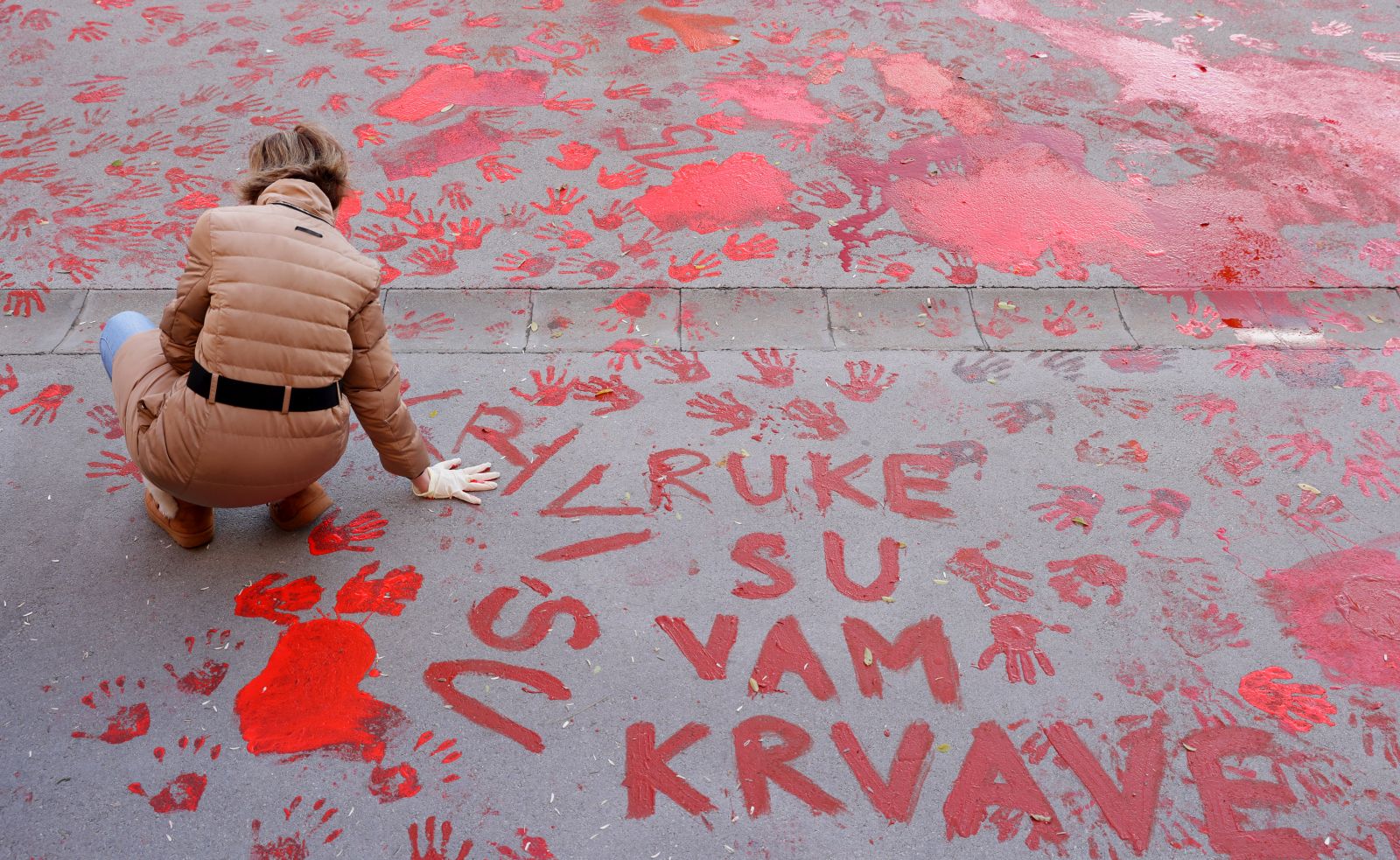 epa11751325 A protestor paints the pavement with red paint symbolizing blood during the one month anniversary of the Novi Sad train station accident in Novi Sad, Serbia, 01 December 2024. Fifteen people lost their lives in the collapse of the Novi Sad Railway Station canopy on 01 November 2024. The station building, which had been renovated and reopened on 05 July 2024, was undergoing further renovations shortly before the collapse.  EPA/ANDREJ CUKIC