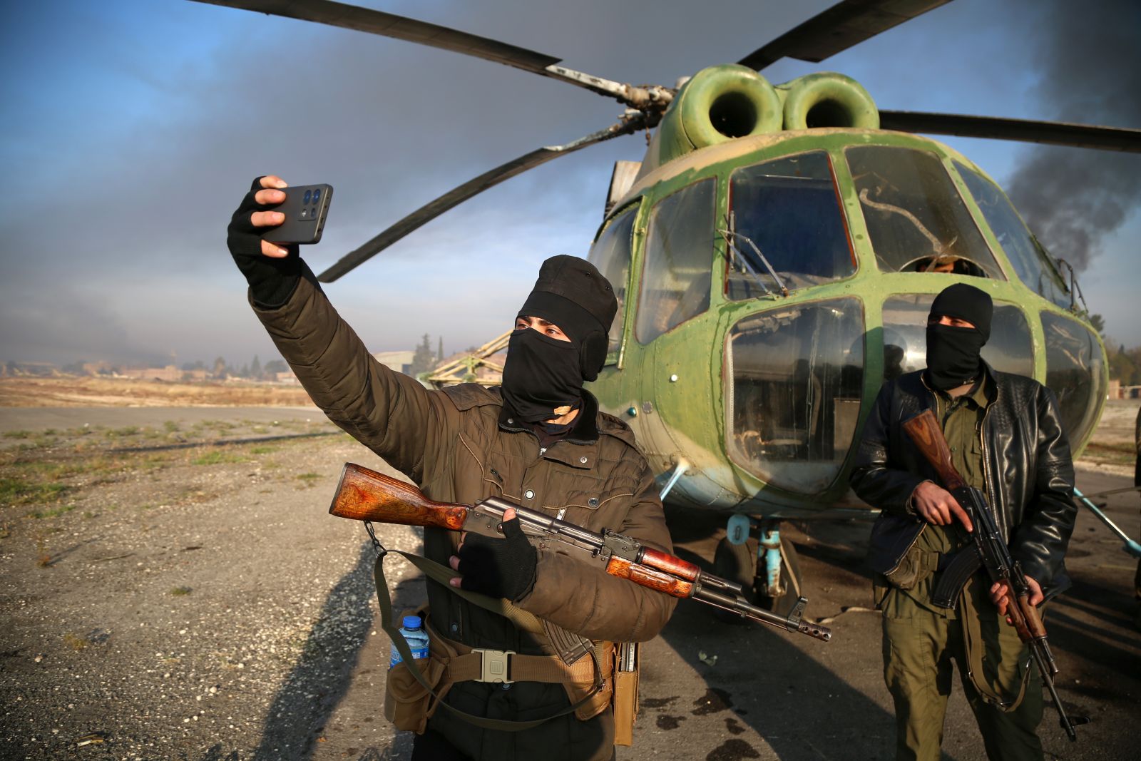 epa11752901 Armed men take selfies at the Nayrab military airport, in Aleppo, Syria, 02 December 2024. Syrian opposition forces, led by the Islamist militant group Hayat Tahrir al-Sham (HTS) launched an offensive on 27 November, taking large parts of Aleppo, Syria's second-largest city. The offensive triggered counterattacks by the Syrian regime forces as well as Russian and Syrian airstrikes on opposition-controlled areas. More than 400 people, including civilians and militants have been killed since 27 November, SOHR stated, while the United Nations Office for the Coordination of Humanitarian Affairs (OCHA) stated that over 20,000 people have been internally displaced within Aleppo and to other governorates.  EPA/BILAL AL HAMMOUD