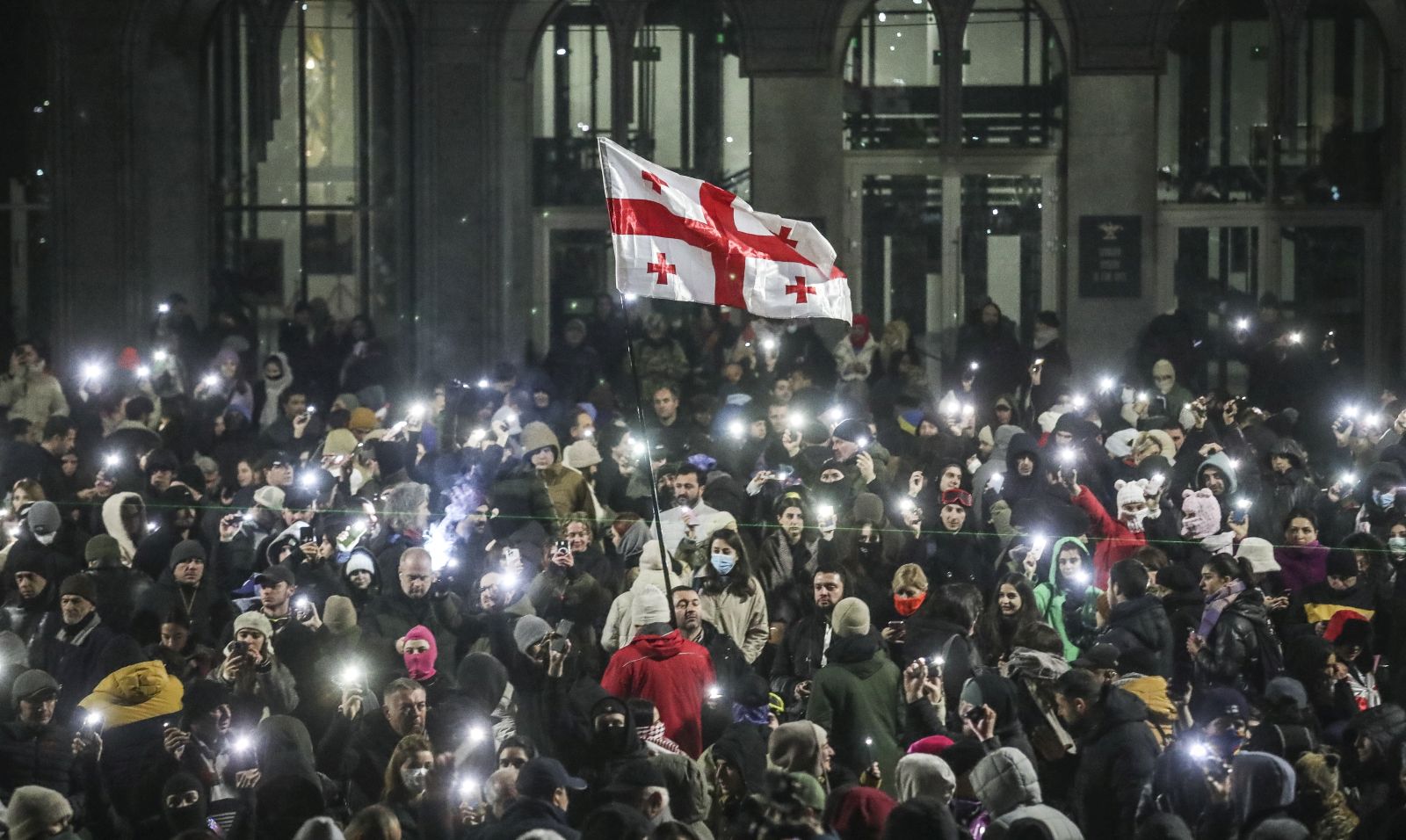 epa11760932 Supporters of the Georgian opposition hold a Georgian flag during a protest in front of the Parliament building in Tbilisi, Georgia, 06 December 2024. Thousands of pro-EU activists continue their protests in the Georgian capital against the country's ruling party decision to suspend accession talks with the European Union (EU) until the end of 2028.  EPA/DAVID MDZINARISHVILI