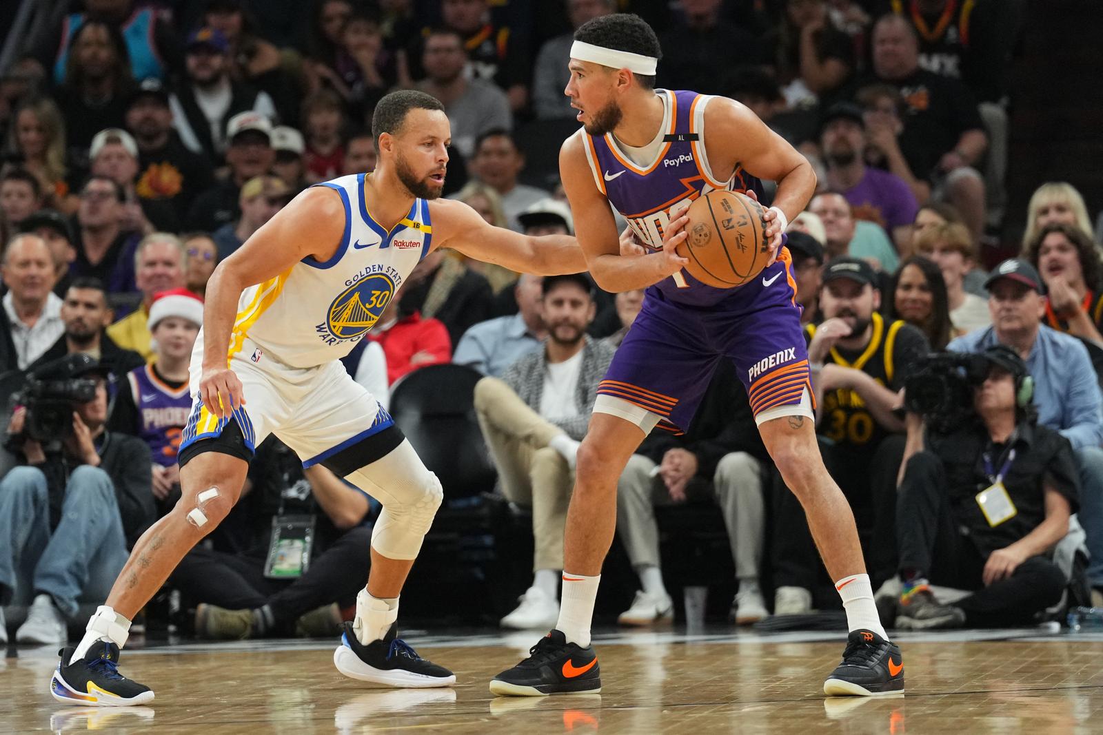 Nov 30, 2024; Phoenix, Arizona, USA; Golden State Warriors guard Stephen Curry (30) guards Phoenix Suns guard Devin Booker (1) during the first half at Footprint Center. Mandatory Credit: Joe Camporeale-Imagn Images Photo: Joe Camporeale/REUTERS