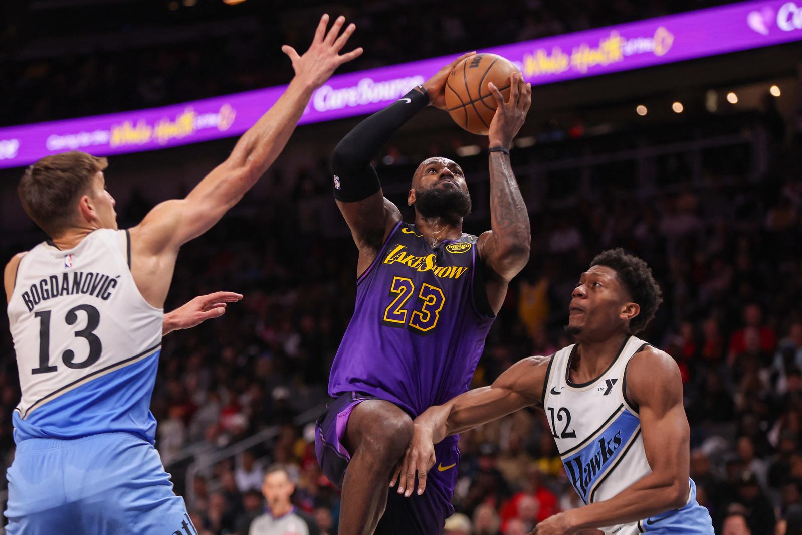 Dec 6, 2024; Atlanta, Georgia, USA; Los Angeles Lakers forward LeBron James (23) shoots past Atlanta Hawks guard Bogdan Bogdanovic (13) and forward De'Andre Hunter (12) in the second quarter at State Farm Arena. Mandatory Credit: Brett Davis-Imagn Images Photo: Brett Davis/REUTERS