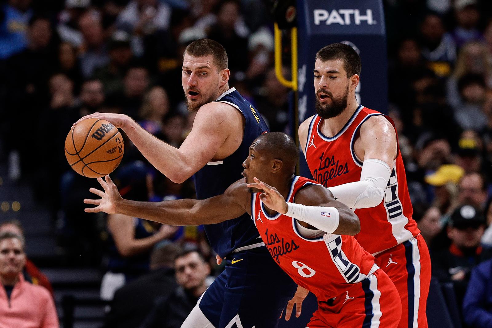 Dec 13, 2024; Denver, Colorado, USA; Los Angeles Clippers guard Kris Dunn (8) attempts to steal the ball away from Denver Nuggets center Nikola Jokic (15) as center Ivica Zubac (40) defends in the second quarter at Ball Arena. Mandatory Credit: Isaiah J. Downing-Imagn Images Photo: Isaiah J. Downing/REUTERS