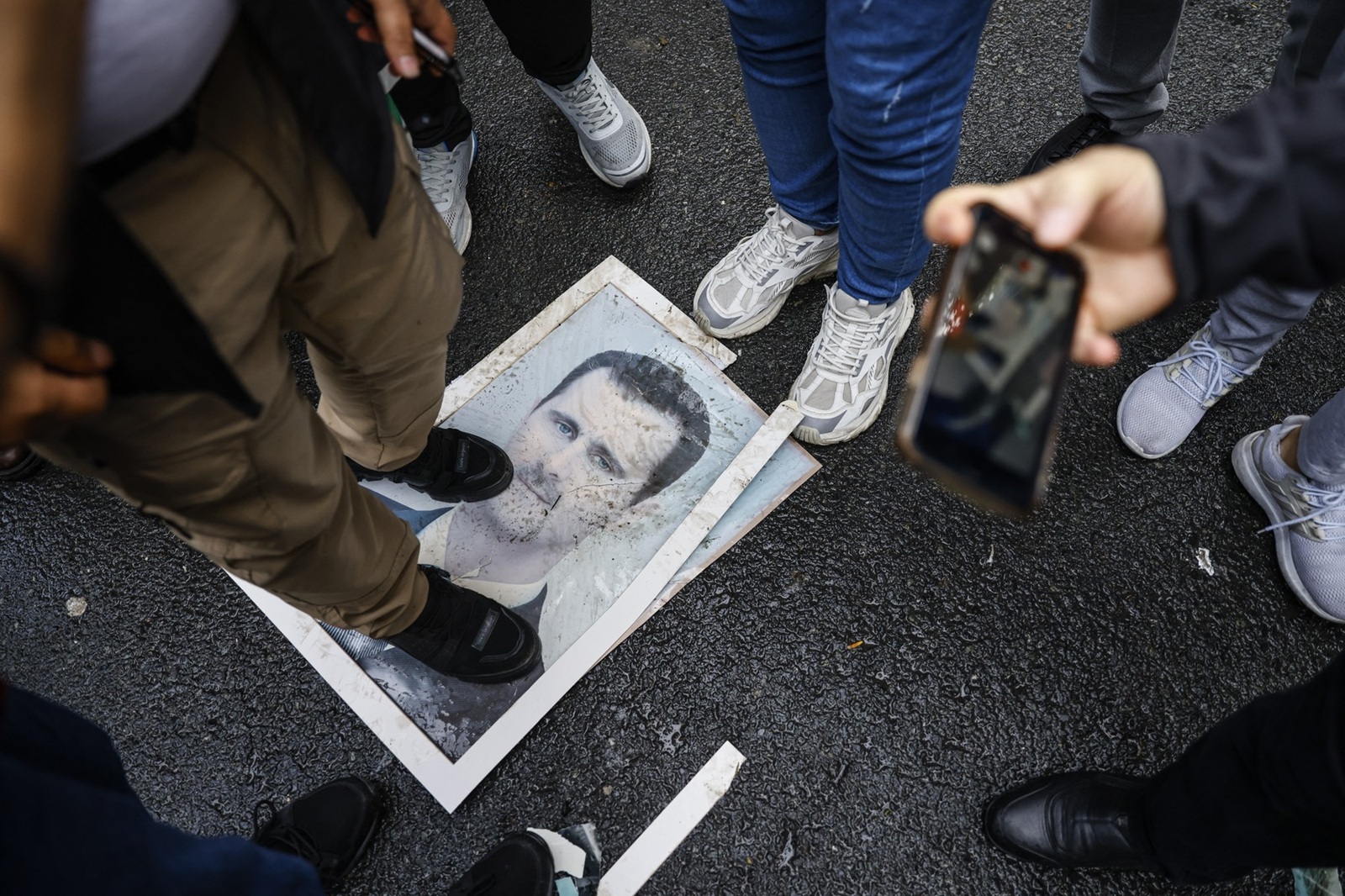 A demonstrator stands on a photograph of President Bashar al-Assad during a protest outside the Syrian consulate in Istanbul on December 8, 2024. Syria's capital woke up on December 8, 2024 to chanting, cheering and gunfire in celebration of the fall of President Bashar al-Assad, after rebels said they entered the city and toppled the longtime ruler. Rebel group Hayat Tahrir al-Sham and allied factions have pressed a lightning offensive since November 27, sweeping swathes of the country from government control, including major cities Aleppo, Hama and Homs and entering the capital Damascus early Sunday.,Image: 944329703, License: Rights-managed, Restrictions: , Model Release: no, Credit line: KEMAL ASLAN / AFP / Profimedia