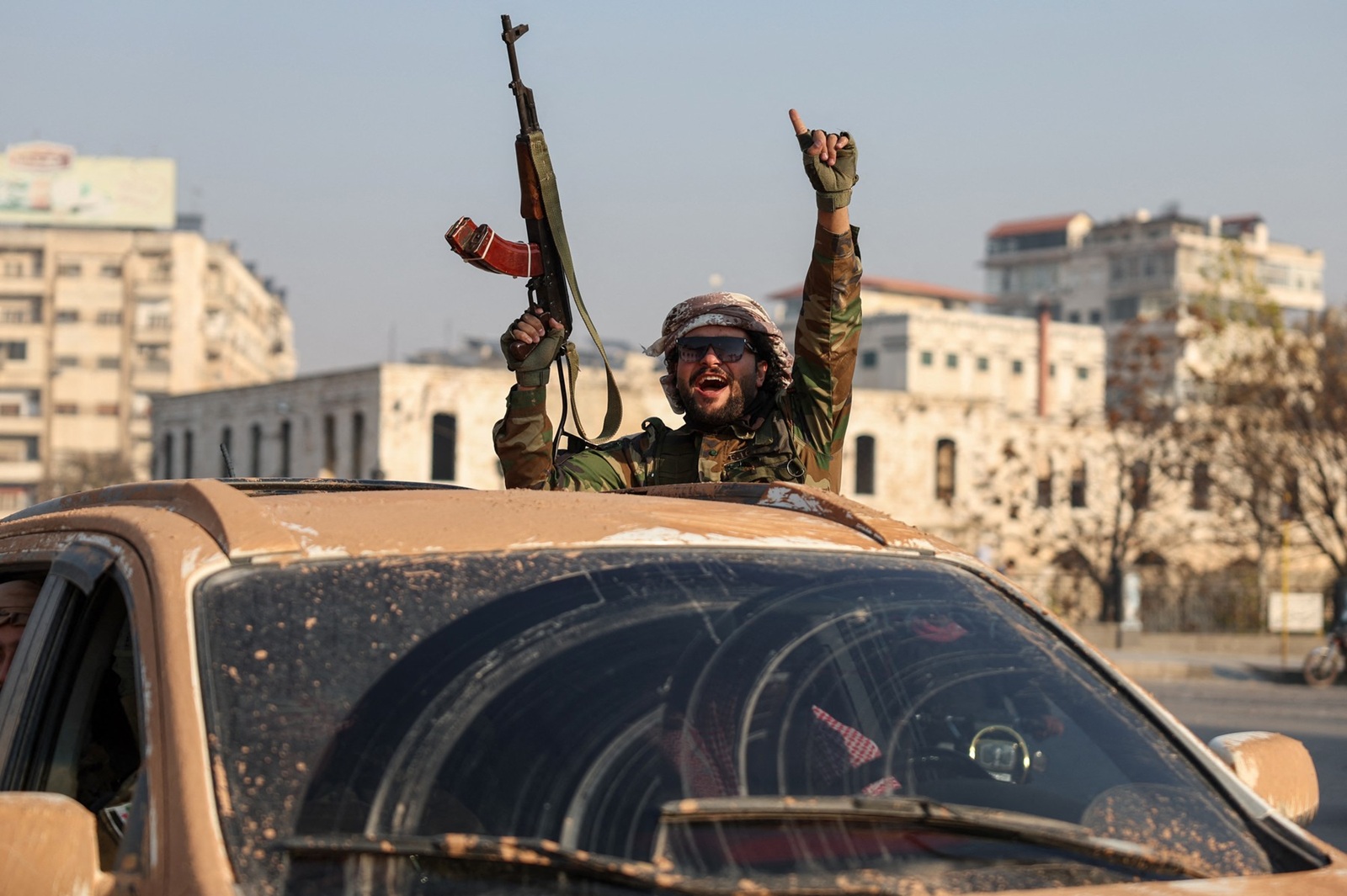 An anti-government fighter gestures from inside a vehicle patrolling the streets of Hama after they captured the central Syrian city, on December 6, 2024. Rebel forces pressing a lightning offensive in Syria aim to overthrow President Bashar al-Assad's rule, their Islamist leader said in an interview published on December 6. In little over a week, the offensive has seen Syria's second city Aleppo and strategically located Hama fall from Assad's control for the first time since the civil war began in 2011.,Image: 943721607, License: Rights-managed, Restrictions: , Model Release: no, Credit line: OMAR HAJ KADOUR / AFP / Profimedia