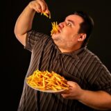 Diet failure of fat man eating fast food . Overweight person who spoiled healthy food by eating french fries. Junk meal leads to obesity. Foods high in fat concept.,Image: 340762735, License: Royalty-free, Restrictions: , Model Release: yes, Credit line: Gennadiy Poznyakov / Alamy / Alamy / Profimedia