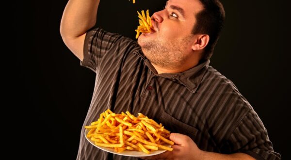 Diet failure of fat man eating fast food . Overweight person who spoiled healthy food by eating french fries. Junk meal leads to obesity. Foods high in fat concept.,Image: 340762735, License: Royalty-free, Restrictions: , Model Release: yes, Credit line: Gennadiy Poznyakov / Alamy / Alamy / Profimedia