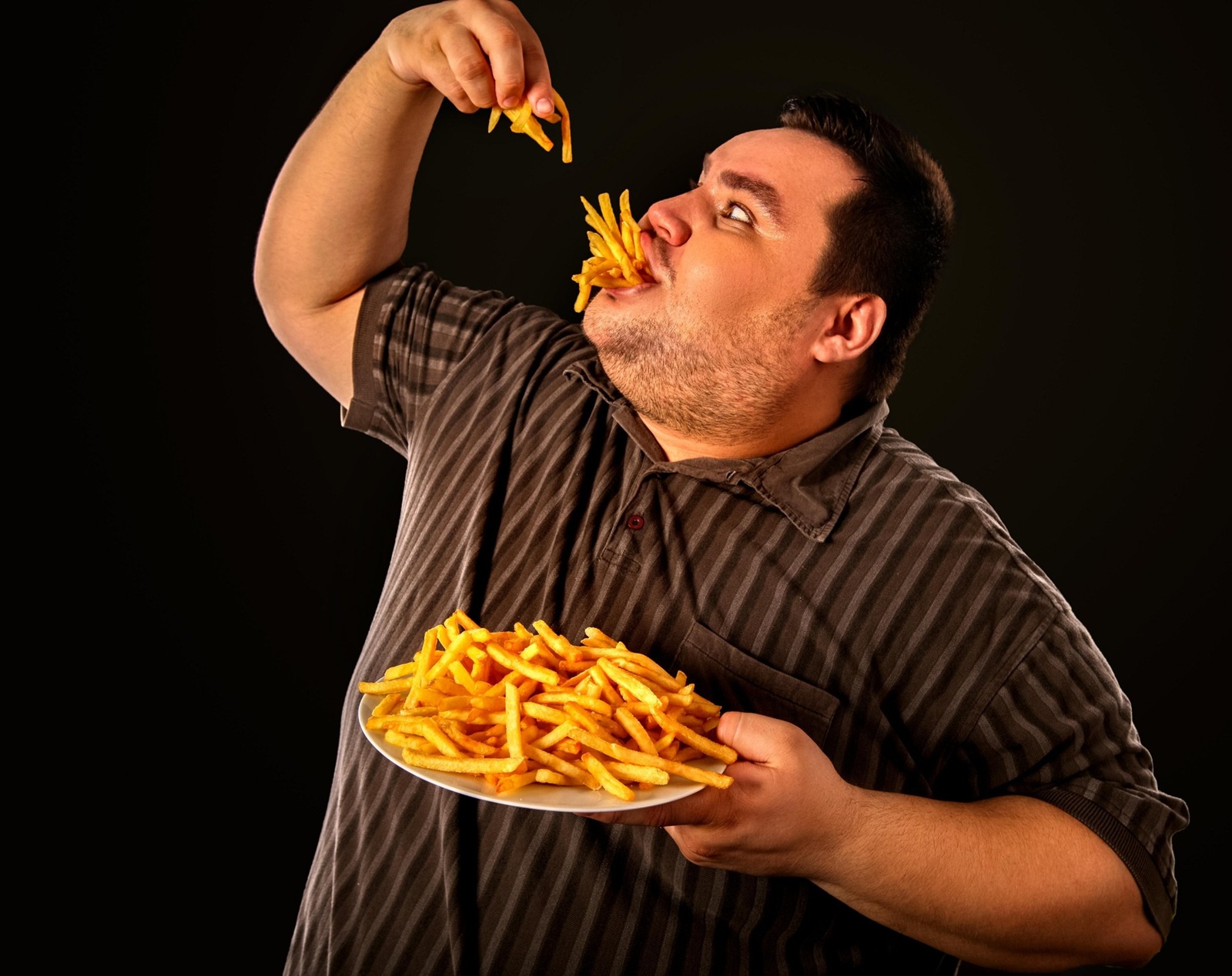 Diet failure of fat man eating fast food . Overweight person who spoiled healthy food by eating french fries. Junk meal leads to obesity. Foods high in fat concept.,Image: 340762735, License: Royalty-free, Restrictions: , Model Release: yes, Credit line: Gennadiy Poznyakov / Alamy / Alamy / Profimedia