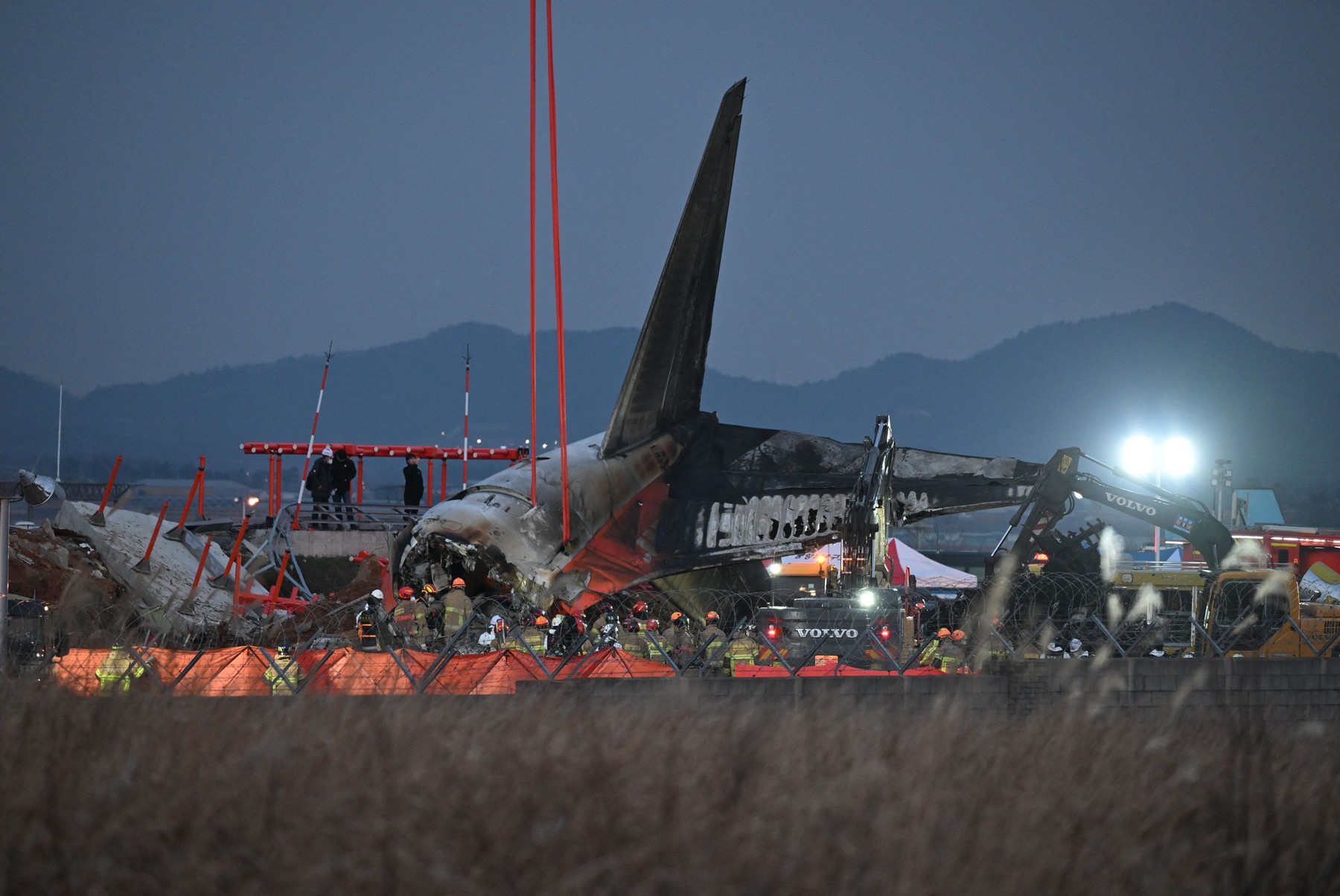 Firefighters and rescue personnel work near the scene where a Jeju Air Boeing 737-800 series aircraft crashed and burst into flames at Muan International Airport in South Jeolla Province, some 288 kilometres southwest of Seoul on December 29, 2024.  A Jeju Air plane carrying 181 people from Thailand to South Korea crashed on arrival, smashing into a barrier and bursting into flames, leaving all but two feared dead.,Image: 950680352, License: Rights-managed, Restrictions: , Model Release: no, Credit line: JUNG YEON-JE / AFP / Profimedia