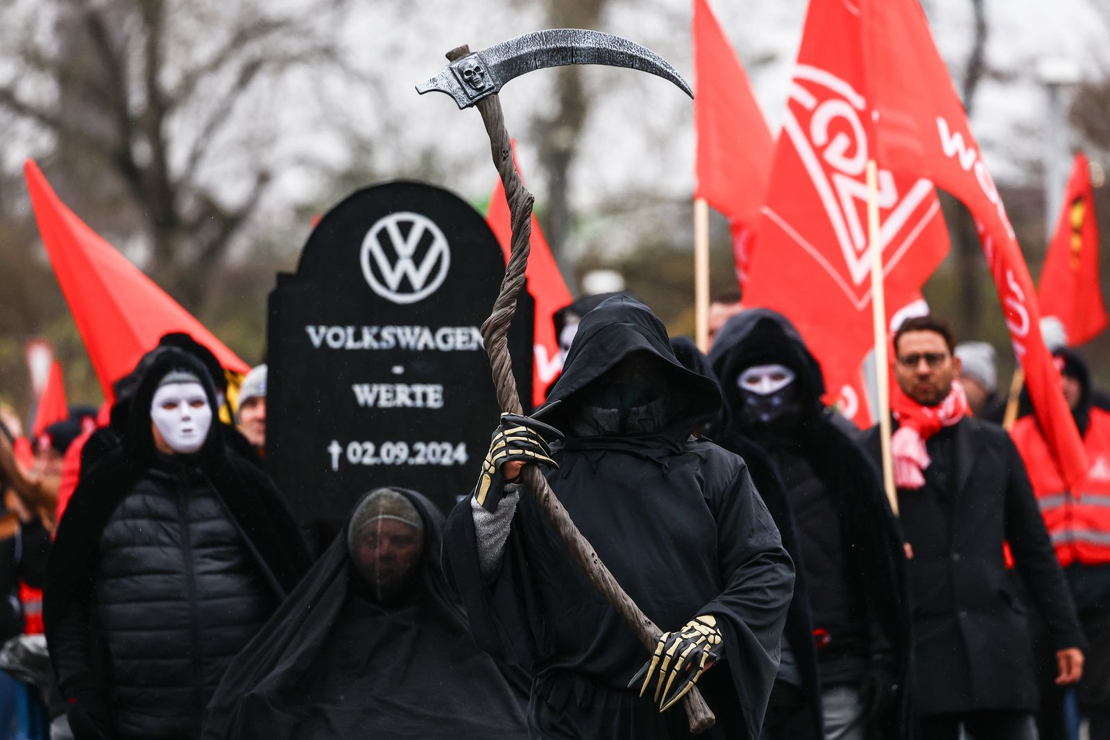 epa11732366 A protestor carries a tombstone for German automobile manufacturer Volkswagen during a protest supporting a third round of wage negotiations between IG Metall and Volkswagen AG, in Wolfsburg, Germany, 21 November 2024. Germany's largest carmaker Volkswagen may close three factories dedicated to its core brand in Germany and reduce employee wages, according to the company's workers council. This announcement sets the stage for a potentially prolonged dispute with unions representing around 120,000 German workers.  EPA/FILIP SINGER