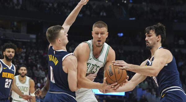 Boston Celtics center Kristaps Porzingis, center, drives to the basket as Denver Nuggets guard Christian Braun, left, and forward Dario Saric defend in the first half of an NBA basketball game, Tuesday, Jan. 7, 2025, in Denver. (AP Photo/David Zalubowski)