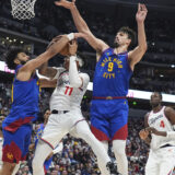 Los Angeles Clippers guard Jordan Miller, center, drives to the basket as Denver Nuggets guard Jamal Murray, left, and forward Dario Saric defend in the second half of an NBA basketball game Wednesday, Jan. 8, 2025, in Denver. (AP Photo/David Zalubowski)