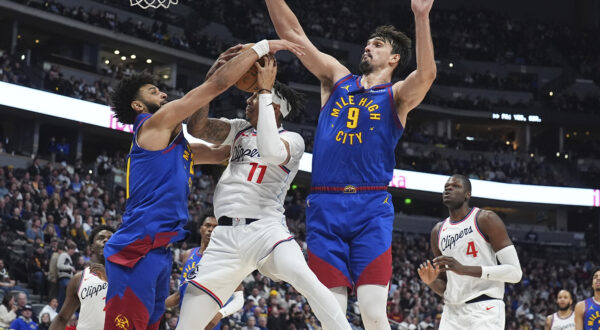 Los Angeles Clippers guard Jordan Miller, center, drives to the basket as Denver Nuggets guard Jamal Murray, left, and forward Dario Saric defend in the second half of an NBA basketball game Wednesday, Jan. 8, 2025, in Denver. (AP Photo/David Zalubowski)