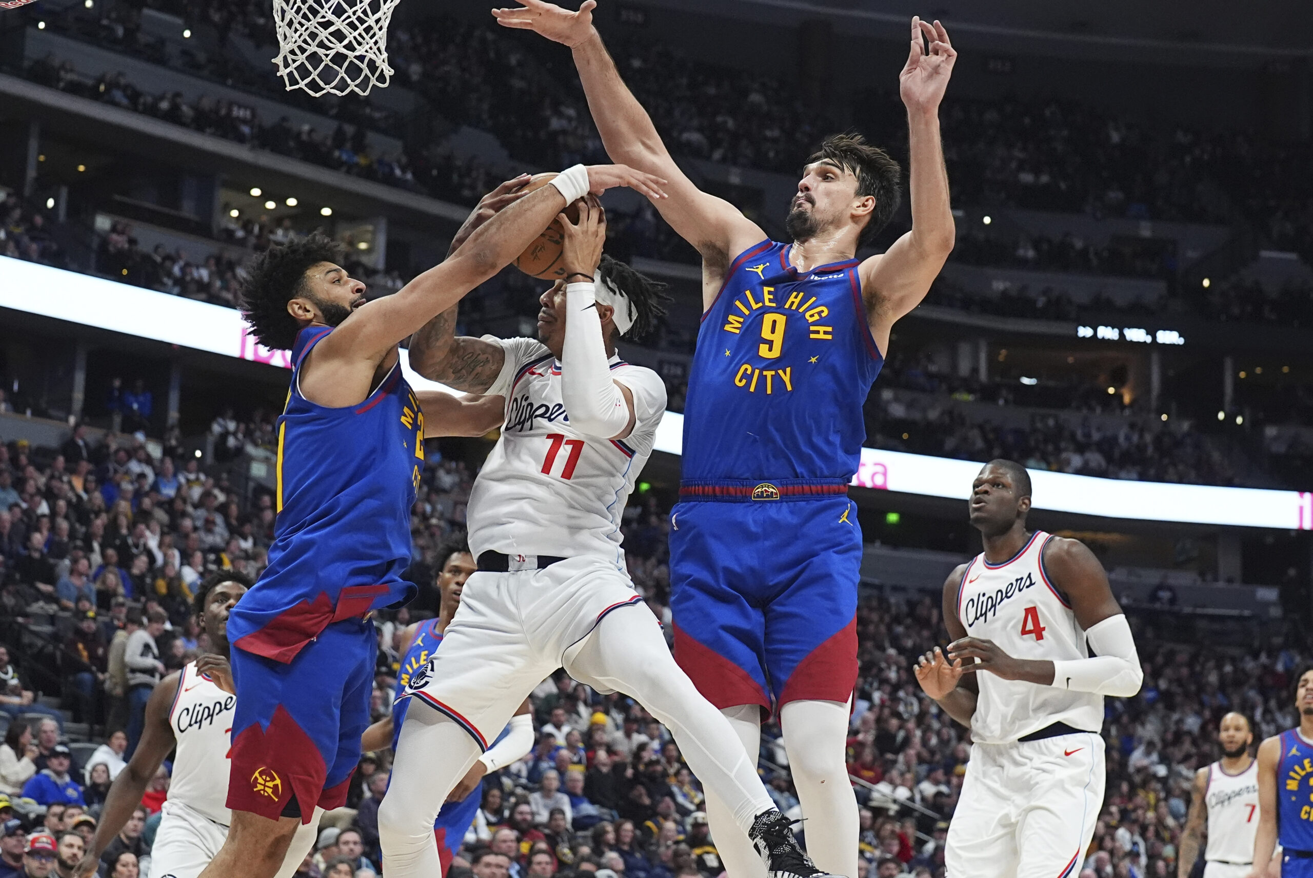 Los Angeles Clippers guard Jordan Miller, center, drives to the basket as Denver Nuggets guard Jamal Murray, left, and forward Dario Saric defend in the second half of an NBA basketball game Wednesday, Jan. 8, 2025, in Denver. (AP Photo/David Zalubowski)