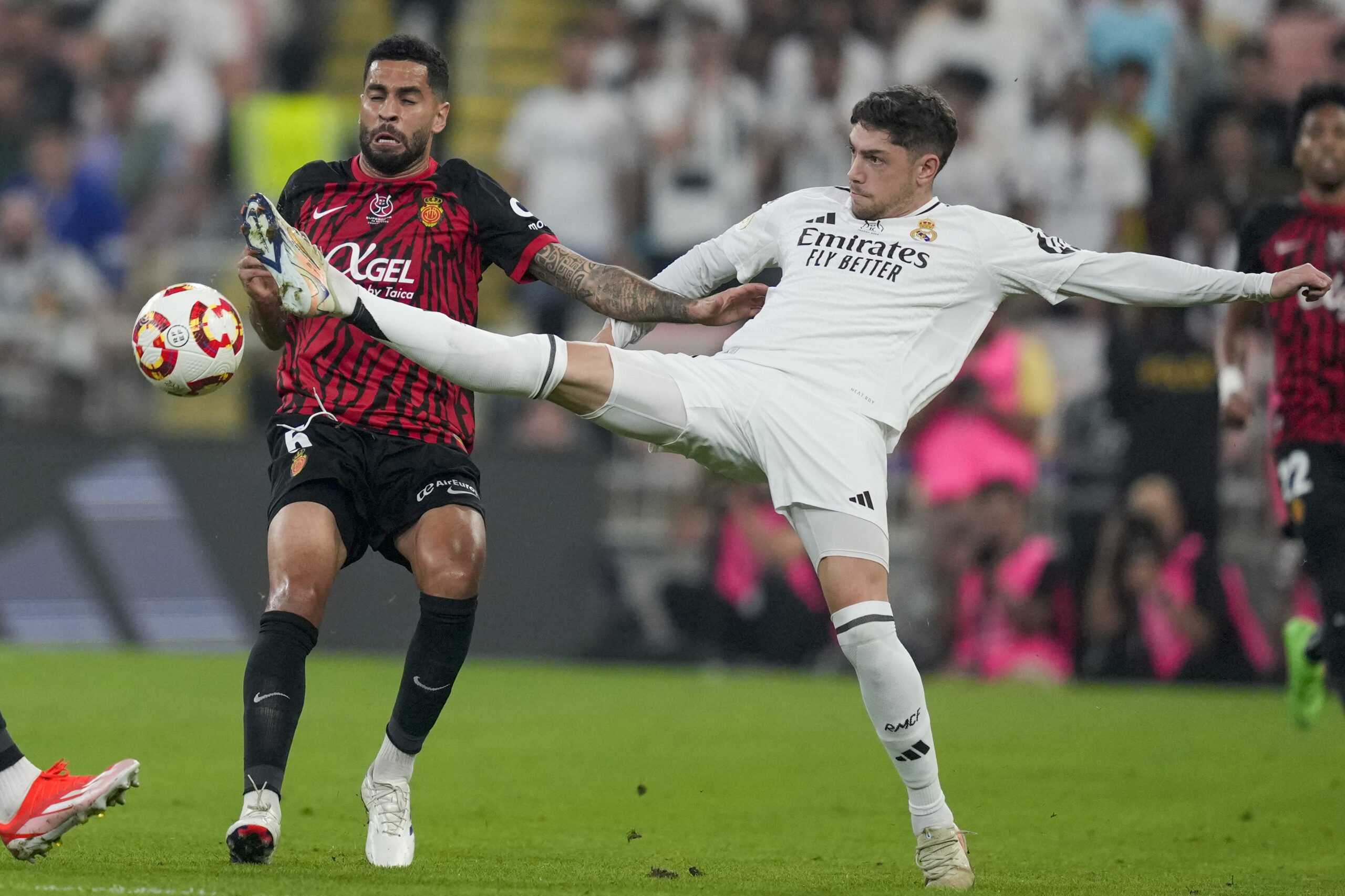 Real Madrid's Federico Valverde, right, is challenged by Mallorca's Omar Mascarell during the Spanish Super Cup semifinal soccer match between Real Madrid and Mallorca at the King Abdullah Stadium in Jeddah, Saudi Arabia, Thursday, Jan. 9, 2025. (AP Photo/Altaf Qadri)