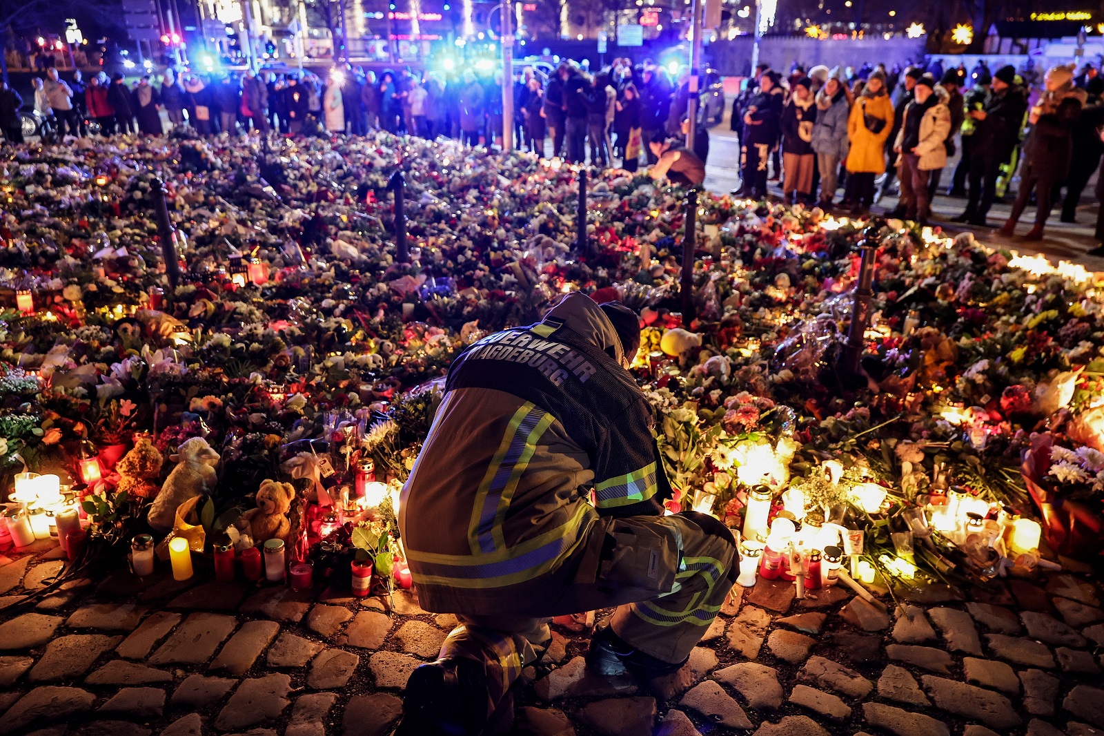 epa11791323 A firefighter in front of candles and flowers at the mourning site in front of St. John's Church following a vehicle-ramming attack on the Christmas market in Magdeburg, Germany, 23 December 2024. According to Saxony-Anhalt State Premier Haseloff, five people were confirmed dead and at least 235 were injured after a car was driven into a crowd at Magdeburg's Christmas market on 20 December. The suspect, a Saudi national, was taken into custody.  EPA/FILIP SINGER