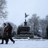 epa11806789 People walk in the snow near the Statue of Eros at Sefton Park in Liverpool, Britain, 05 January 2025. The Met Office has issued a yellow warning for snow and ice across nearly all of Britain, with a more severe amber snow warning in place throughout much of northern Britain and Wales.  EPA/ADAM VAUGHAN