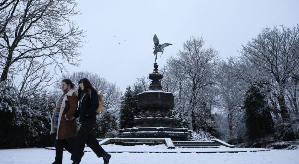 epa11806789 People walk in the snow near the Statue of Eros at Sefton Park in Liverpool, Britain, 05 January 2025. The Met Office has issued a yellow warning for snow and ice across nearly all of Britain, with a more severe amber snow warning in place throughout much of northern Britain and Wales.  EPA/ADAM VAUGHAN