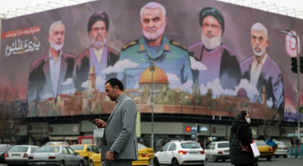 epa11808827 Iranians walk past a billboard with the pictures of late Iranian Islamic Revolutionary Guard Corps (IRGC) Quds Force commander Qasem Soleimani (C), late Hamas leaders Ismail Haniyeh (L) and Yahya Sinwar (R), and late Hezbollah leader Hasan Nasrallah (2-R), and the head of Hezbollah's executive council Hashem Safieddine (2-L), and a sentence reading in Persian 'God wrote our duty, help to the oppressed' hanging at the Enghelab square in Tehran, Iran, 06 January 2025.  EPA/ABEDIN TAHERKENAREH