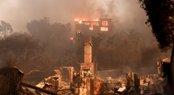 epa11813471 A house on fire and the remains of another burnt home in an area affected by the Palisades wildfire in Malibu, California, USA, 08 January 2025. According to data from California Department of Forestry and Fire Protection, CAL FIRE, the Palisades fire has burned through thousands of acres and has forced tens of thousands of evacuations in the Los Angeles area.  EPA/ALLISON DINNER