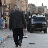 epa11816836  Palestinian man walks pass Israeli troops during army operation at Qabaitya village near the West Bank city of Jenin, 10 January 2025. Several Palestinians were wounded during the operation, according to the Palestinian Health Ministry.  EPA/ALAA BADARNEH